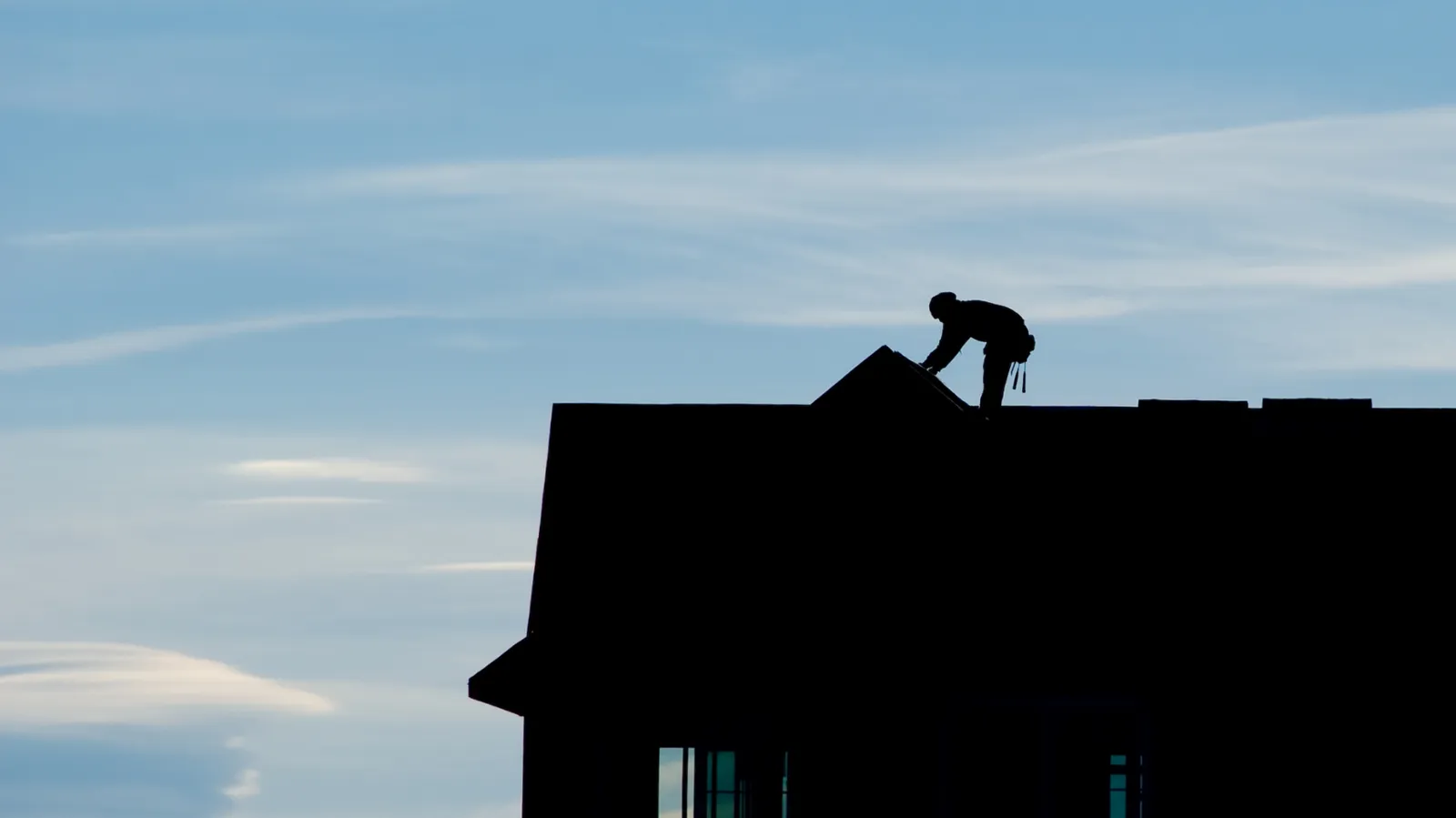 House roof ridge with a distant silhouetted roofer