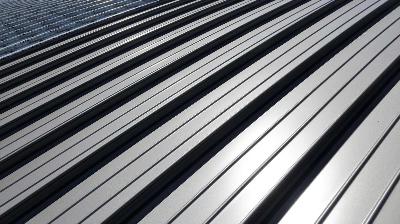 Standing seam metal roof panels reflecting sunlight